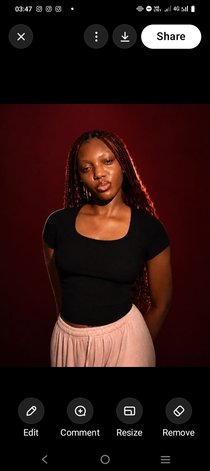 Portrait of a woman with long red braids in a black top on a deep red backdrop